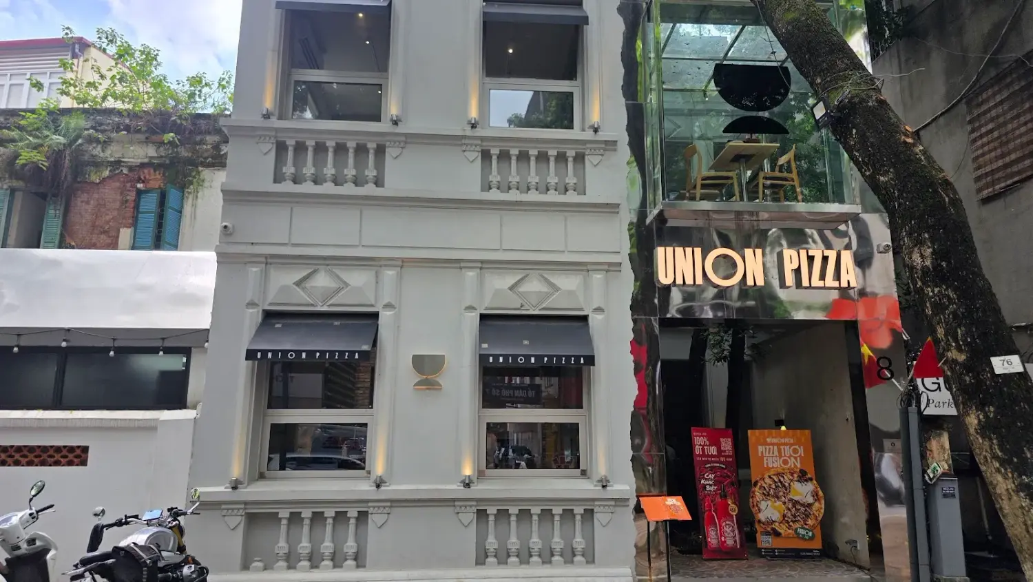 Mặt tiền Union Pizza bằng thép gương phản chiếu hàng cây và biệt thự Pháp phố Phan Đình Phùng